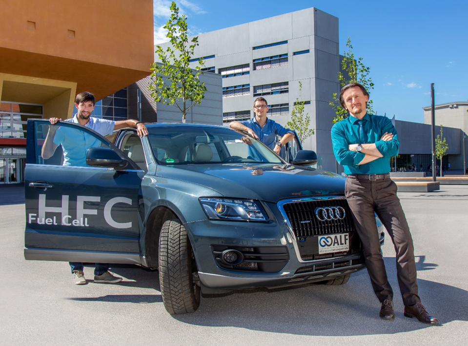 Professur Thomas von Unwerth von der Technischen Universität Chemnitz mit den wissenschaftlichen Mitarbeitern Martin Uhlmann und Christian Schmidt vor einem Brennstoffzellenfahrzeug